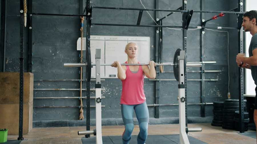 Woman lifting barbell with trainer watching