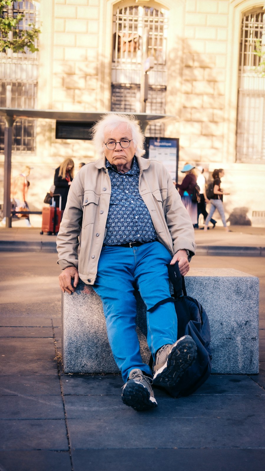 Elderly man with white hair sits with guitar case